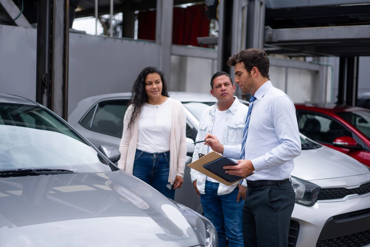 trois personnes qui discutent de la vente aux enchères d'une voiture