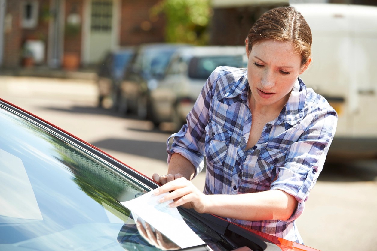 femme surprise par une contravention de stationnement sur son pare-brise