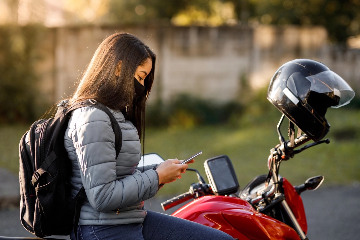 jeune femme consultant son téléphone sur sa moto 