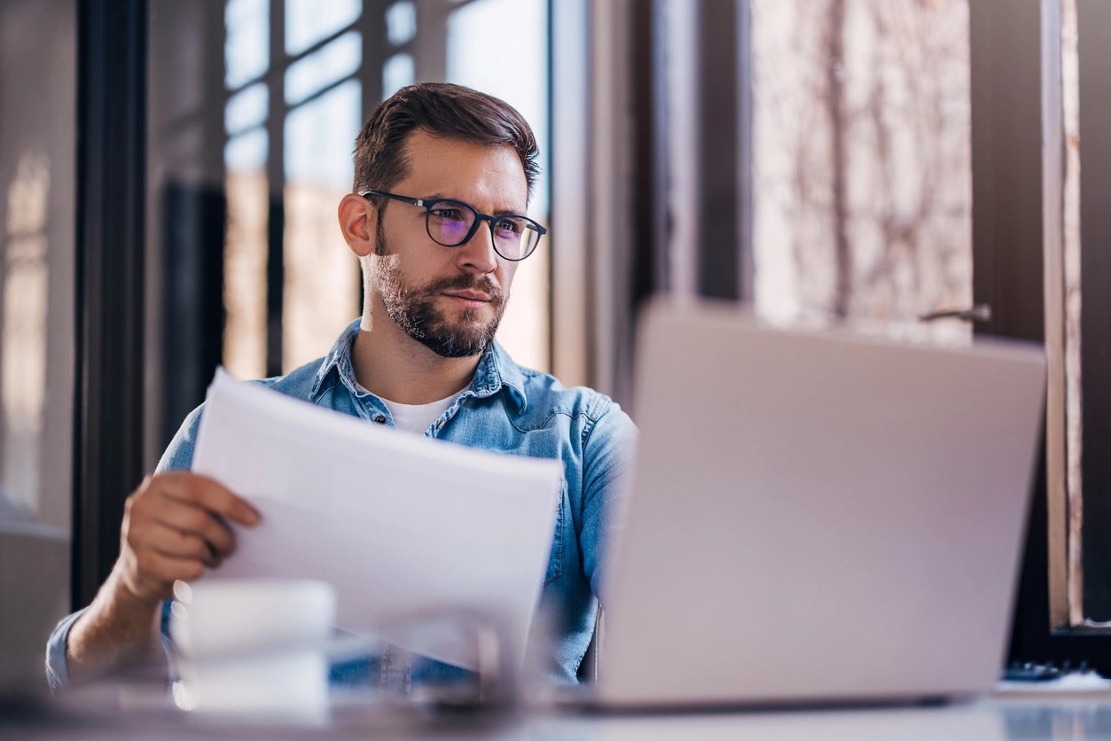 homme à lunettes qui recherche sur son ordinateur