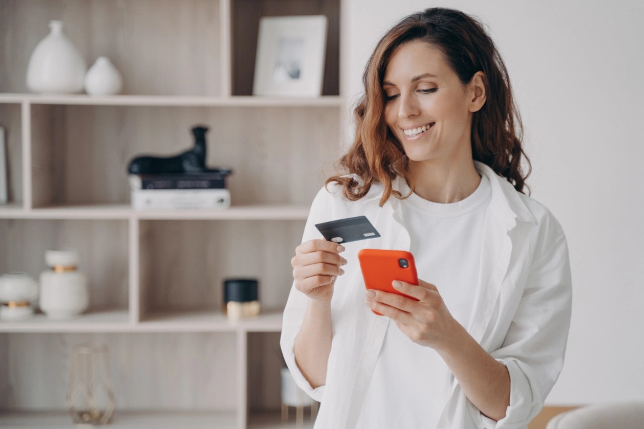 Femme brune souriante payant un service en ligne sur son smartphone