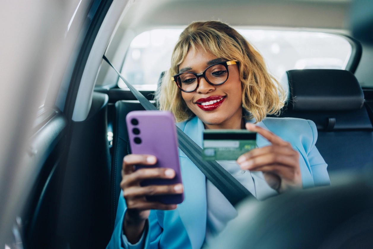 Femme heureuse faisant des achats en ligne avec une carte de crédit dans la voiture 
