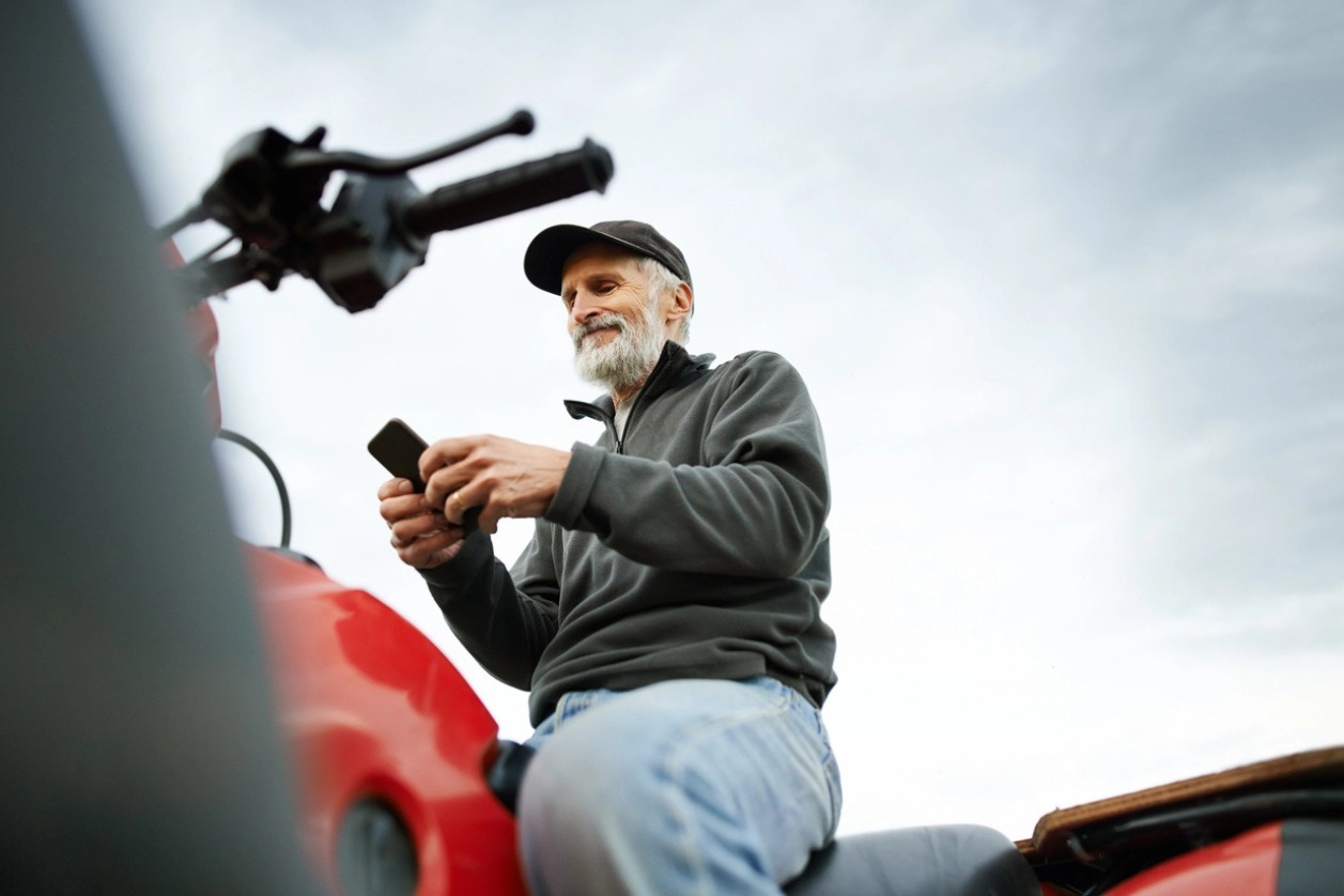 homme âgé consultant son smartphone assis sur son quad