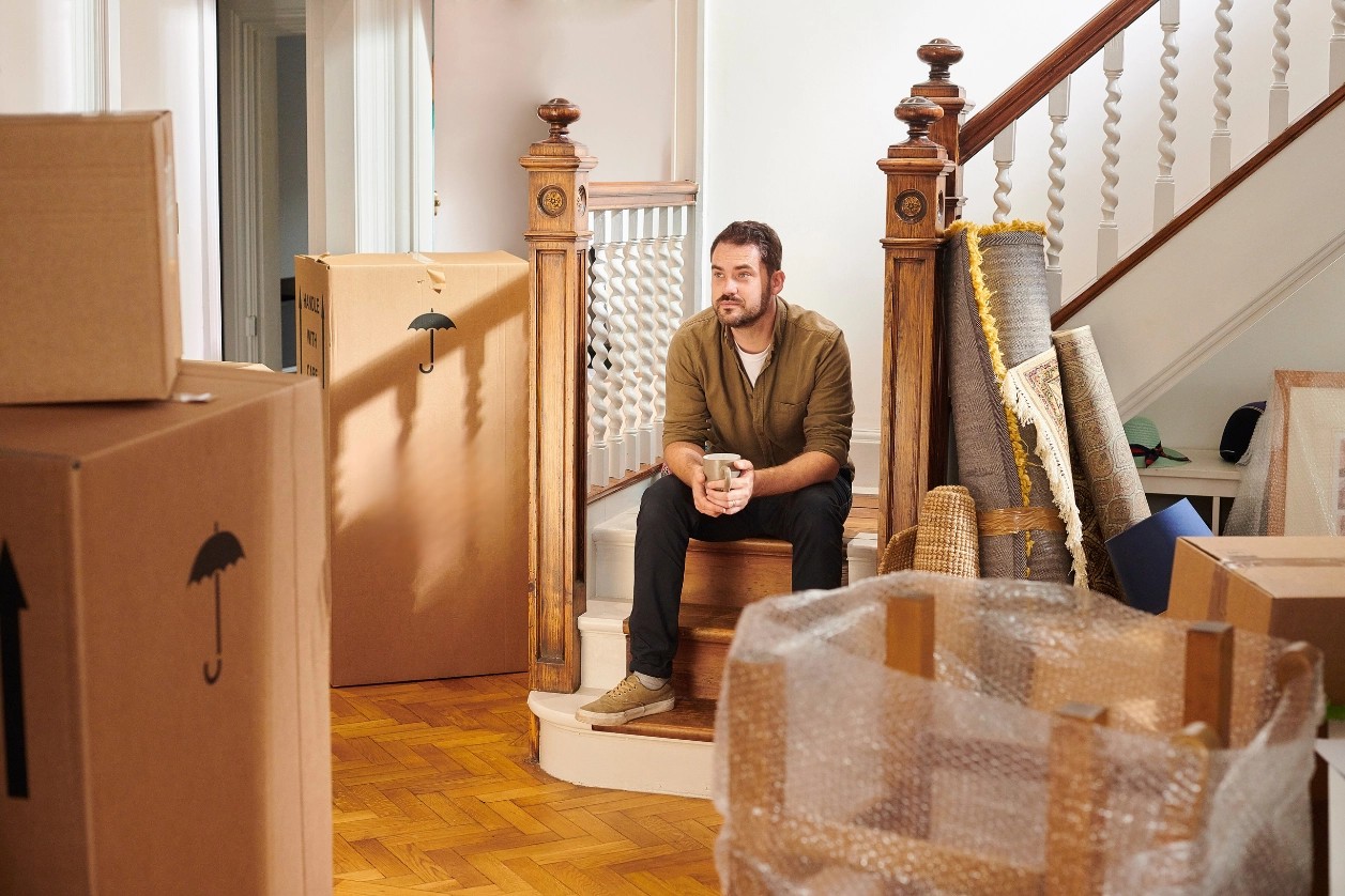 homme soucieux regardant ses cartons de déménagement 